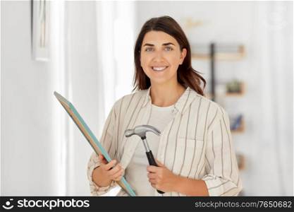 home improvement, decoration and people concept - happy smiling woman with hammer and picture in frame. woman with hammer and picture in frame at home