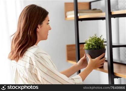 home improvement, decoration and people concept - woman placing flower or houseplant to shelf. woman decorating home with flower or houseplant