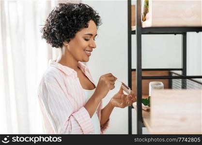 home improvement, decoration and people concept - woman with matchsticks lighting candles on shelf. woman with matchsticks lighting candles at home