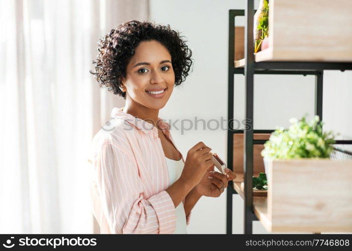 home improvement, decoration and people concept - woman with matchsticks lighting candles on shelf. woman with matchsticks lighting candles at home