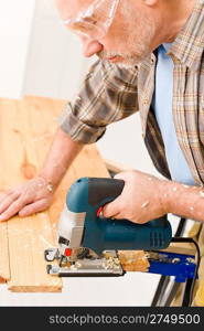 Home improvement - handyman cut wood with jigsaw in workshop