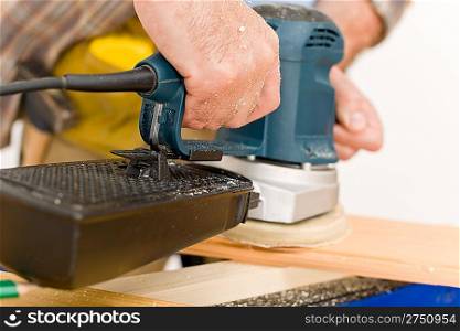 Home improvement - handyman sanding wooden floor in workshop