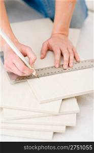 Home improvement - handywoman measuring tile, focus on ruler
