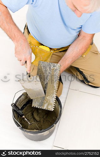 Home improvement, renovation - handyman laying tile, trowel with mortar