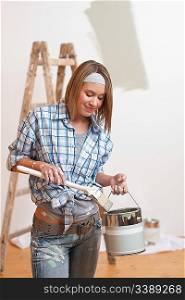 Home improvement: Smiling woman with paint and brush painting wall