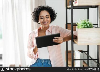 home improvement, technology and people concept - happy smiling woman with tablet pc computer standing at shelf. smiling woman with tablet pc computer at home