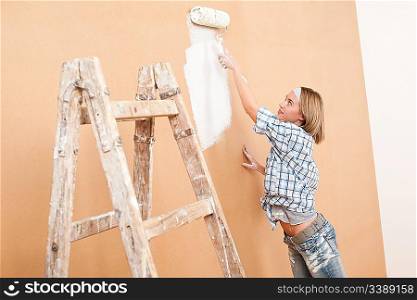 Home improvement: Woman painting wall with paint roller