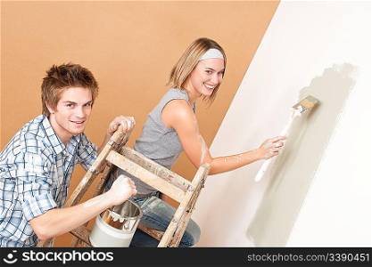 Home improvement: Young couple painting wall with paint brush