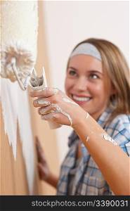 Home improvement: Young woman painting wall with paint roller
