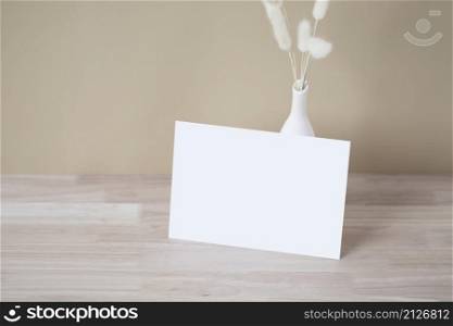 Home interior floral decor, pampas grass on table, Front view, blank paper card, Greeting card Mockup. Beautiful white pampas grass in vase on wood background