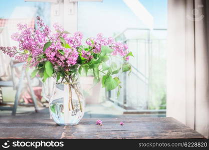 Home interior with Bouquet of blooming lilac flowers on the table in front of window