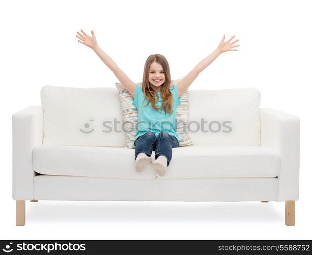 home, leisure and happiness concept - smiling little girl sitting on sofa and waving hands