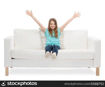 home, leisure and happiness concept - smiling little girl sitting on sofa and waving hands