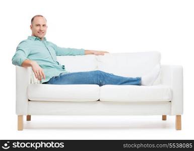 home, leisure and happiness concept - smiling man lying on sofa