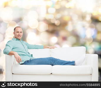 home, leisure and happiness concept - smiling man lying on sofa