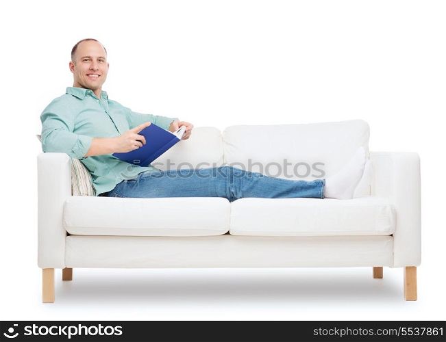 home, leisure and happiness concept - smiling man lying on sofa with book