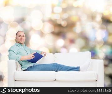 home, leisure and happiness concept - smiling man lying on sofa with book