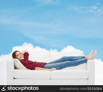 home, leisure and happiness concept - smiling teenage girl lying on sofa