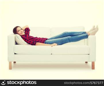 home, leisure and happiness concept - smiling teenage girl lying on sofa