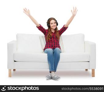 home, leisure and happiness concept - smiling teenage girl sitting on sofa with headphones