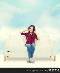 home, leisure and happiness concept - smiling teenage girl sitting on sofa with headphones