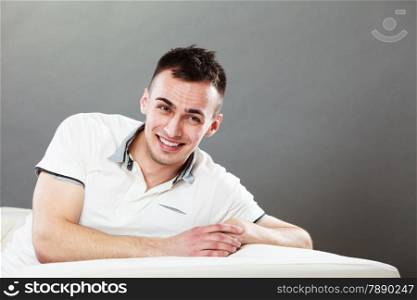 Home, leisure and happiness concept. Young handsome smiling man relaxing on couch