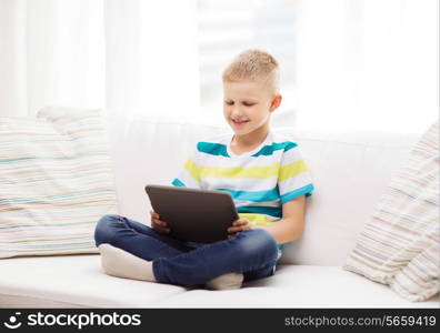 home, leisure and new technology concept - smiling little boy with tablet pc computer at home