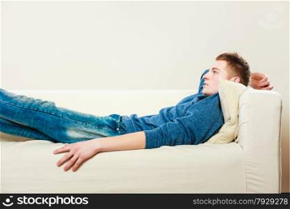 Home, leisure concept. Young handsome pensive man relaxing on couch laying and dreaming