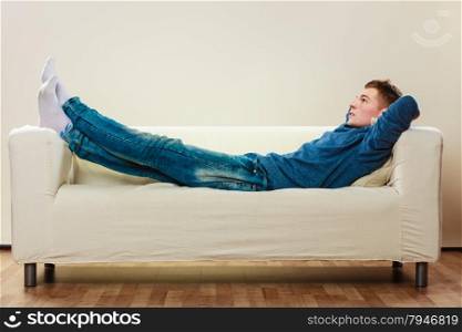 Home, leisure concept. Young handsome pensive man relaxing on couch laying and dreaming