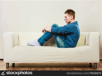 Home, leisure concept. Young handsome pensive man sitting on couch thinking