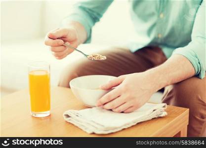 home, leisure, food and people concept - close up of man eating breakfast sitting on couch at home