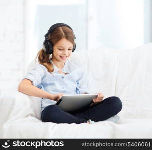 home, leisure, new technology and music concept - smiling little girl with tablet pc computer and headphones at home