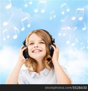 home, leisure, new technology and music concept - smiling little girl with headphones over blue sky background and music notes