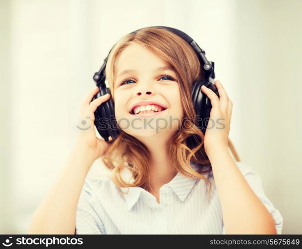 home, leisure, new technology and music concept - smiling little girl with headphones at home