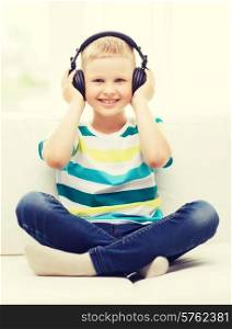 home, leisure, new technology, childhood and music concept - smiling little boy with headphones at home
