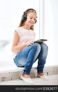 home, leisure, new technology, music concept - little girl with tablet pc and headphones at home