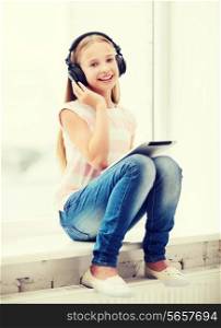 home, leisure, new technology, music concept - little girl with tablet pc and headphones at home