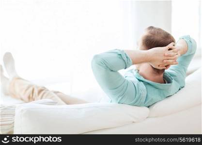 home, leisure, relax and happiness concept - man lying or sitting on sofa at home from back