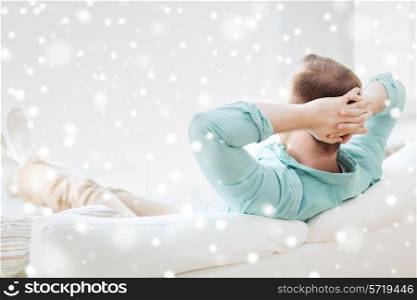 home, leisure, relax and happiness concept - man lying or sitting on sofa at home from back