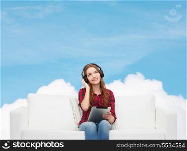 home, leisure, technology and happiness concept - smiling teenage girl sitting on sofa with headphones and tablet pc computer
