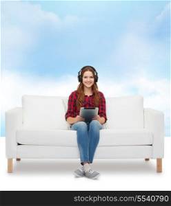 home, leisure, technology and happiness concept - smiling teenage girl sitting on sofa with headphones and tablet pc computer