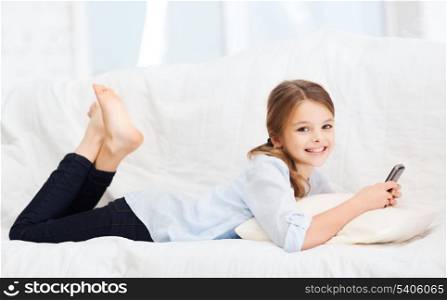 home, leisure, technology and internet concept - little student girl with smartphone at home