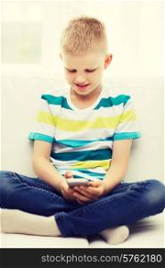 home, leisure, technology and internet concept - smiling little boy with smartphone at home