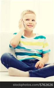 home, leisure, technology and internet concept - smiling little boy with smartphone at home
