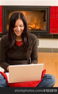 Home living happy young woman by fireplace working on laptop
