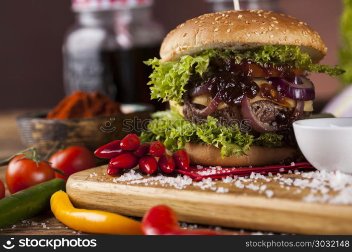 Home made burgers on wooden background. Closeup of homemade hamburger with fresh vegetables