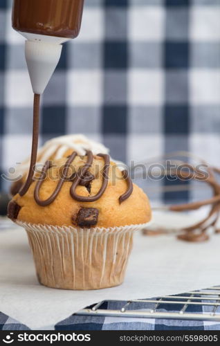 Home made chocolate chip muffins with icing frosting being applied