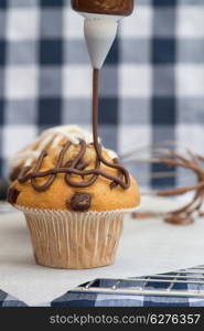 Home made chocolate chip muffins with icing frosting being applied