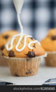 Home made chocolate chip muffins with icing frosting being applied