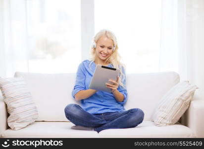 home, music, technology and internet concept - smiling woman lying on the couch with tablet pc computer and headphones at home